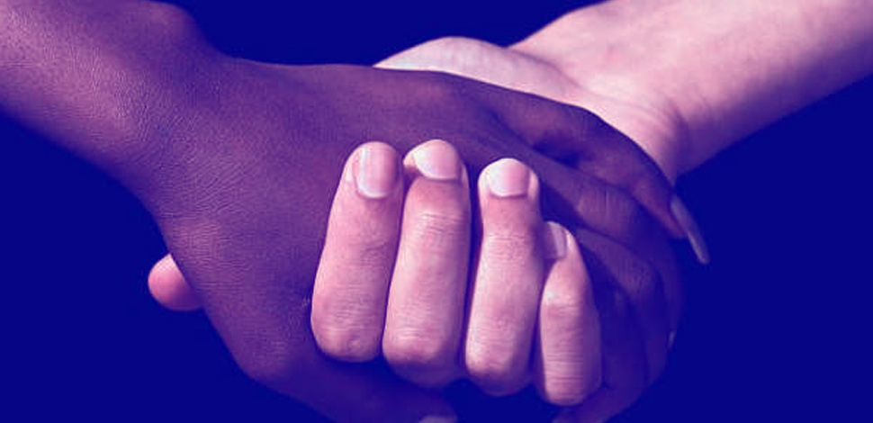 Mãos dadas entre uma pessoa negra e outra branca